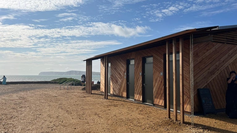 Image of toilet block with sedum roof and background of cliffs